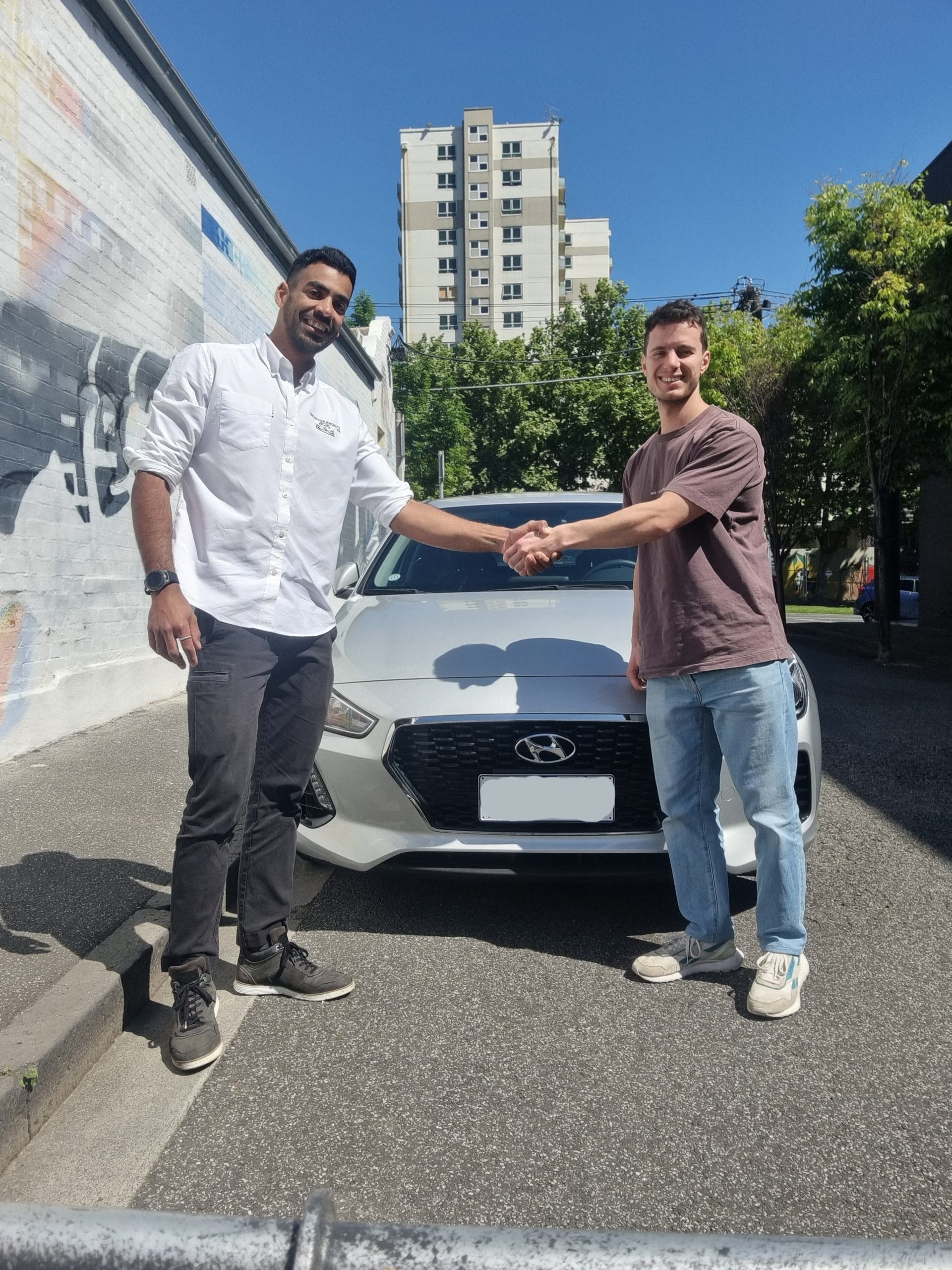 Handshake in front of a white car