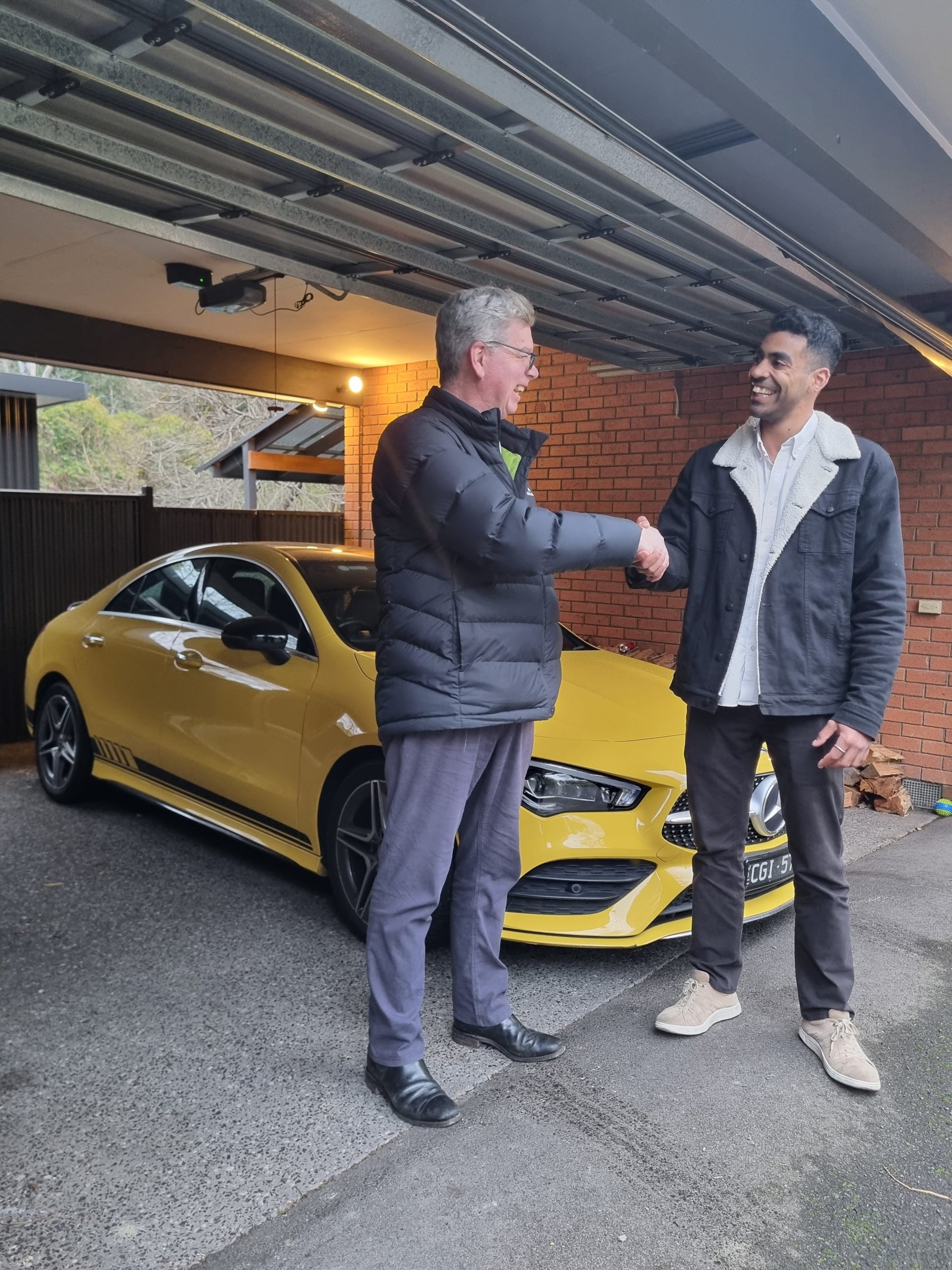 Handshake beside a yellow car